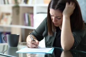 sad woman sigining document complaining sitting in the living room at home